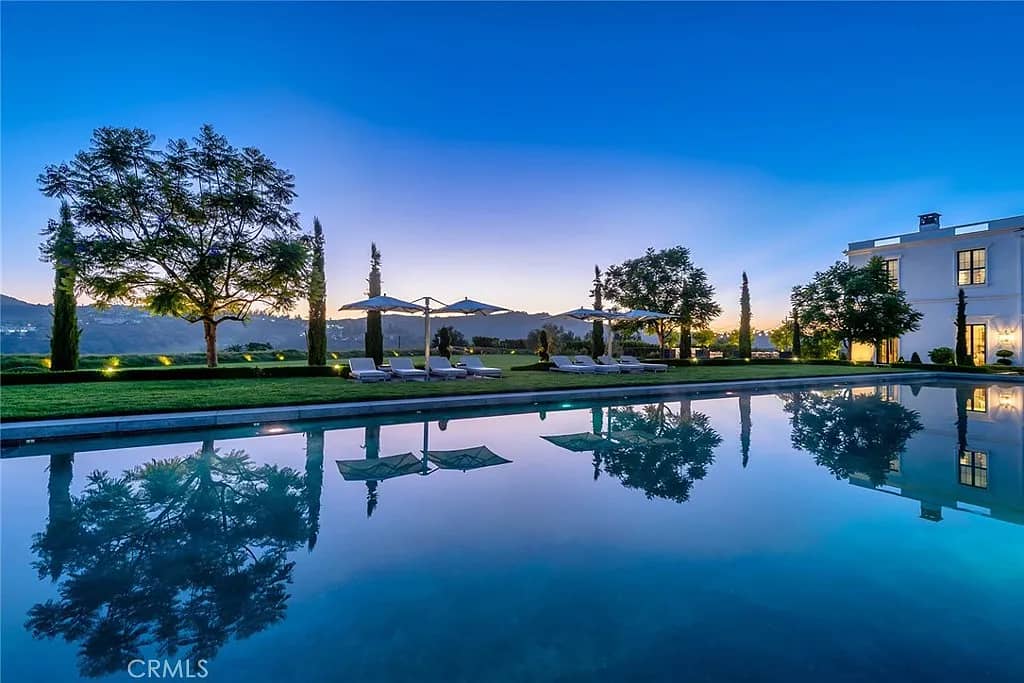 Reflective pool with cypress trees and mountain lake view at dusk