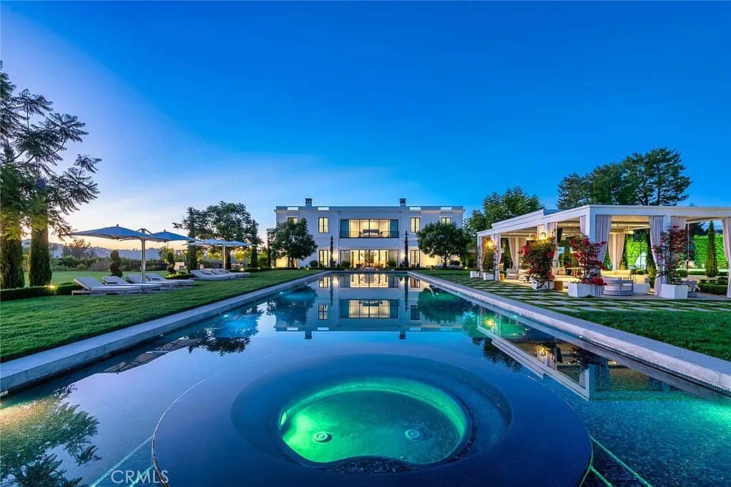 Luxury estate with illuminated pool and mountainous landscape at twilight